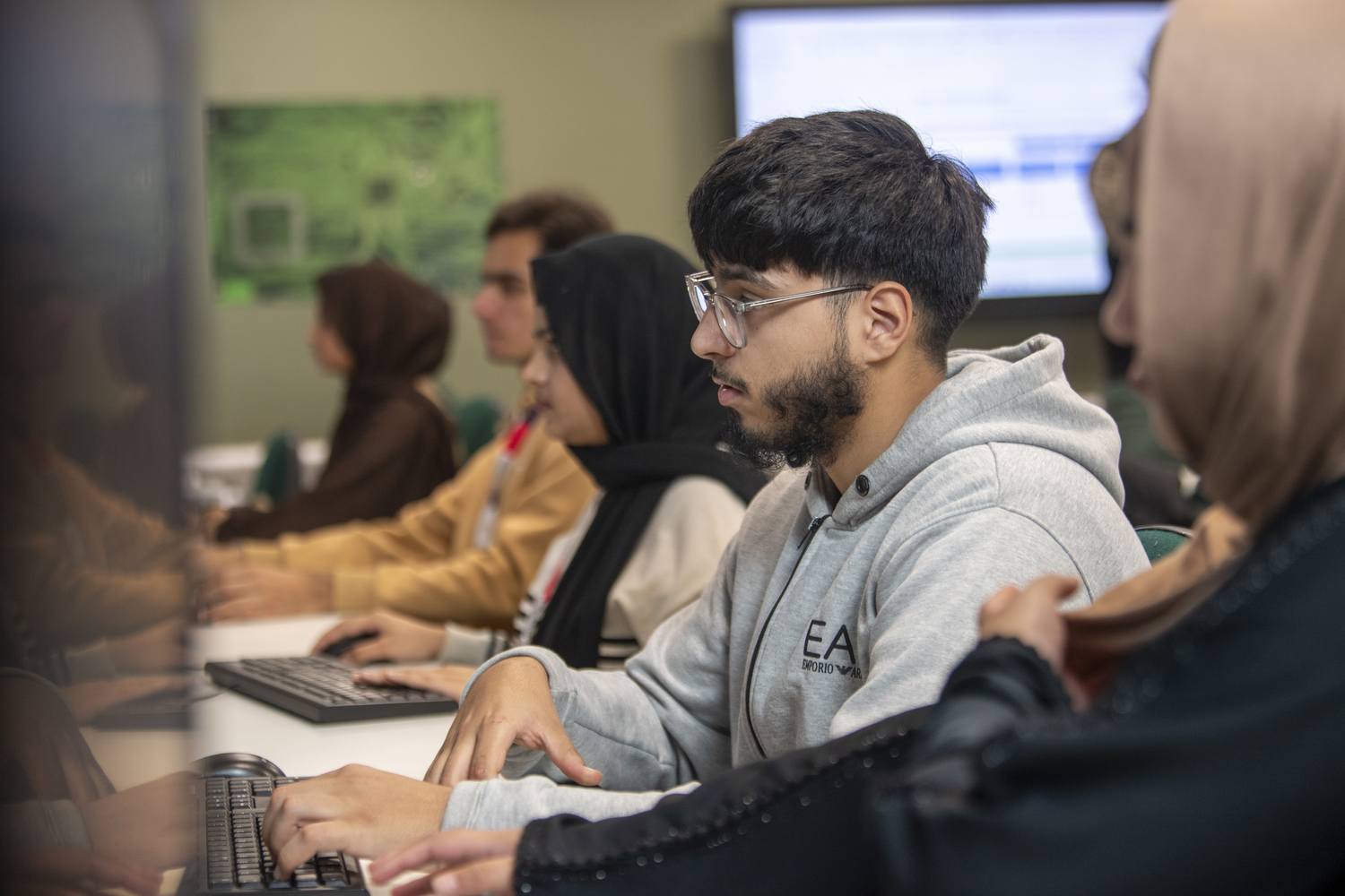 Students in a computer lab, focused on their screens, engaged in a learning activity.